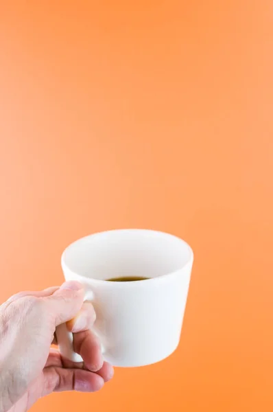 Tiro Vertical Uma Pessoa Segurando Uma Xícara Café Fundo Laranja — Fotografia de Stock