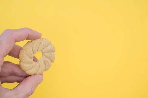 コピースペース付きの黄色の背景に太陽型のクッキーを持つ手 — ストック写真