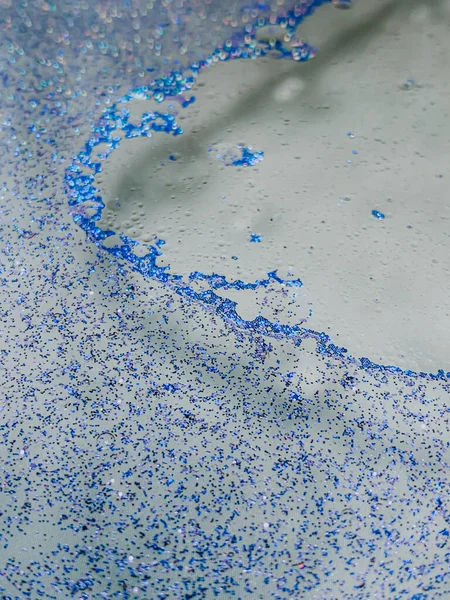 一个蓝色的闪光和水滴的垂直镜头 — 图库照片