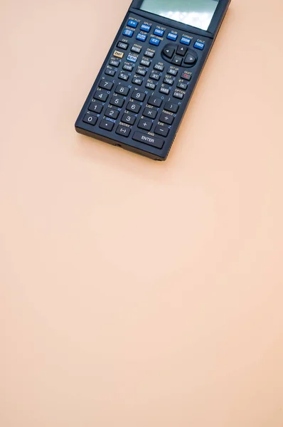 Eine Vertikale Aufnahme Eines Taschenrechners Auf Einem Pfirsichfarbenen Hintergrund — Stockfoto