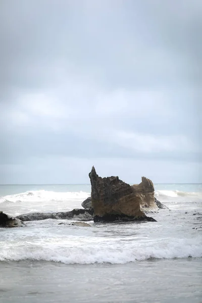 Вертикальний Знімок Хвиль Піни Ламаються Біля Скелястого Моря — стокове фото