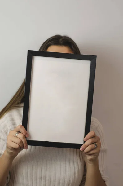 Pionowe Ujęcie Kobiety Trzymającej Biały Pusty Papier Czarną Ramą Zakrywającą — Zdjęcie stockowe