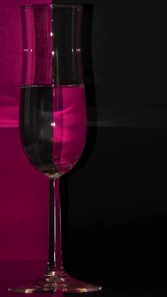 一杯水在紫色和黑色背景上垂直拍摄的照片 — 图库照片