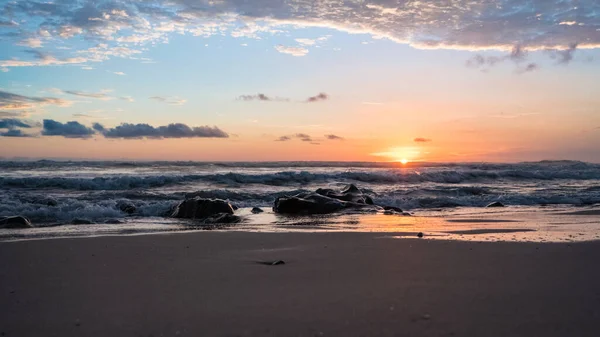 Een Prachtig Uitzicht Een Zonsondergang Schuimgolven Die Rotsachtige Kust Raken — Stockfoto