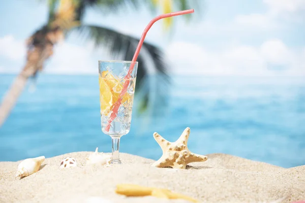 Een Glas Citroenwater Geplaatst Het Zand Een Palmboom Oceaan Achtergrond — Stockfoto