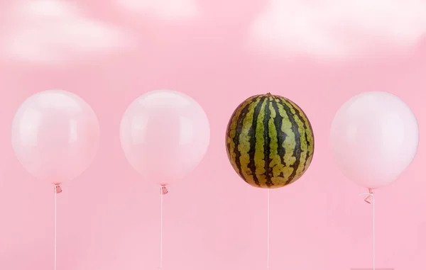 Three white balloons and one watermelon on a pink background