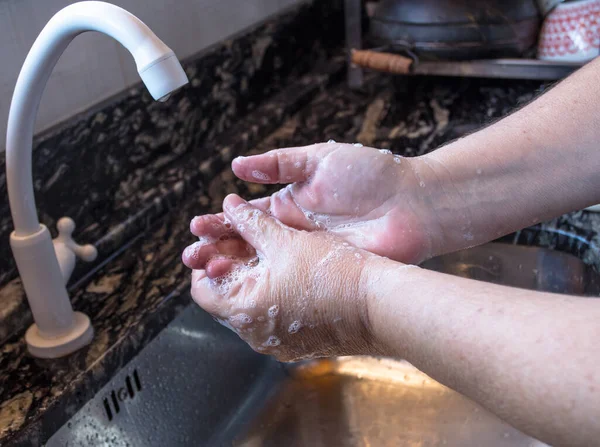 19の大流行によって引き起こされるロックダウン中に台所の石鹸で彼女の手を洗う女性 — ストック写真