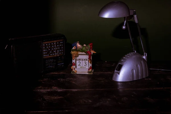 在深色背景下 桌上放着一盏灯和收音机的老式日历的特写镜头 — 图库照片