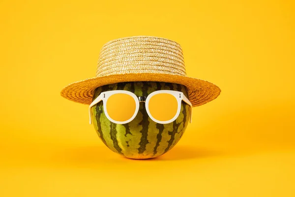 A cool image of watermelon with sunglasses and hat isolated on a yellow background - summertime concept