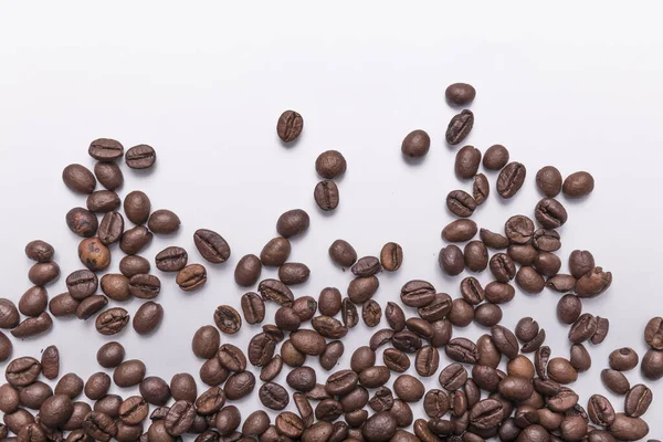 テキストのための部屋と白い表面に散乱茶色の様々な色合いのローストコーヒー豆 コーヒーの背景や食感のコンセプト — ストック写真