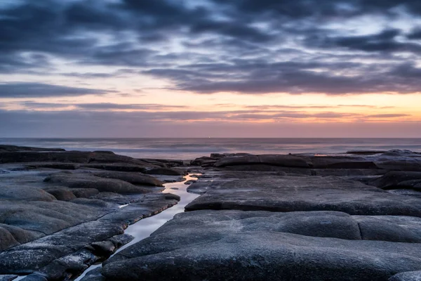 Ein Schöner Sonnenuntergang Über Einem Welligen Meer Mit Steinen — Stockfoto