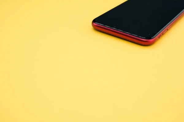 Ένα Κοντινό Πλάνο Ενός Μαύρου Και Κόκκινου Smartphone Κίτρινο Φόντο — Φωτογραφία Αρχείου