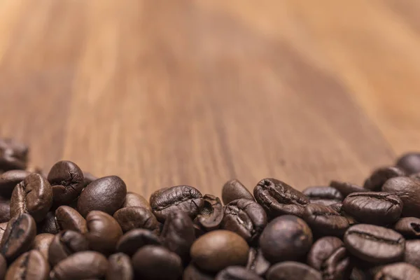 中央の選択的フォーカス 茶色の異なる色合いのコーヒー豆は 専用の木製の表面に散在し 上部に書くためのスペース — ストック写真