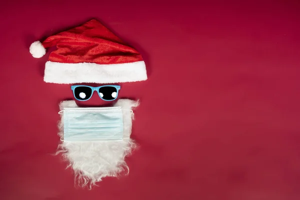Высокоугольный Снимок Шляпы Бороды Санта Клауса Хирургической Маской Красной Поверхности — стоковое фото