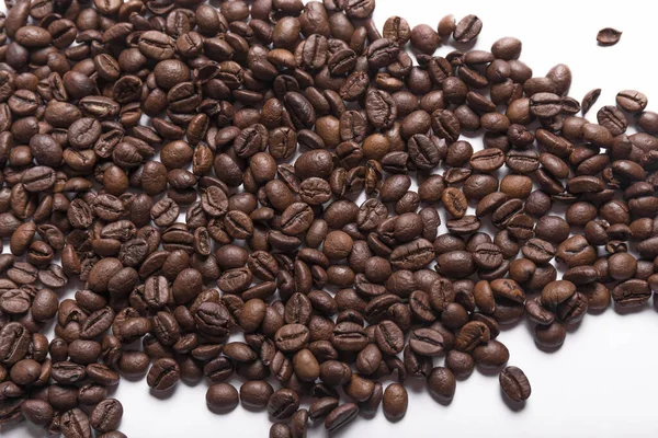 白い表面に散在する茶色の様々な色合いの焙煎コーヒー豆 コーヒーの背景や食感のコンセプト — ストック写真
