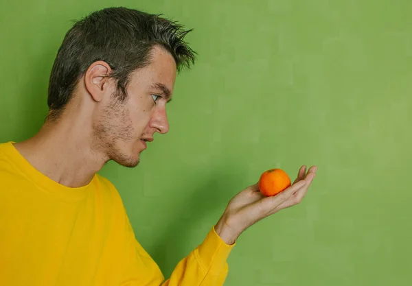 Ein Junger Mann Einem Gelben Sweatshirt Mit Mandarine Der Hand — Stockfoto