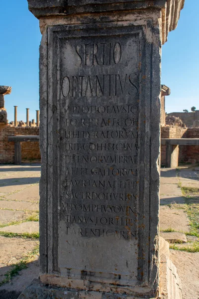 アルジェリアのティムガドにある有名なローマの遺跡の壁に書かれた文章の垂直方向のショー — ストック写真