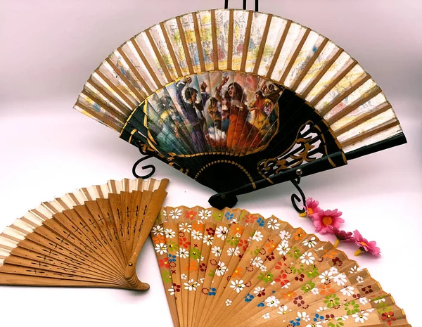 A closeup of old decorated Chinese fans isolated on a gray background