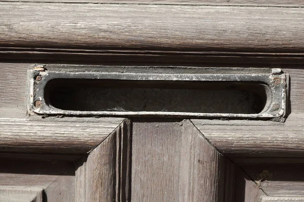 A closeup shot of old metal mail slot on brown oor