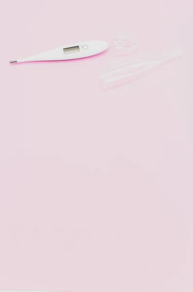 A vertical shot of digital thermometer on pink background with space for your text - disease control concept