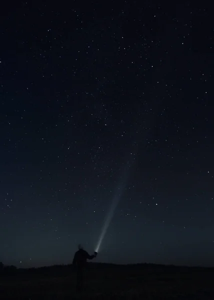 星空の下で懐中電灯を持っている男性の垂直ショット — ストック写真