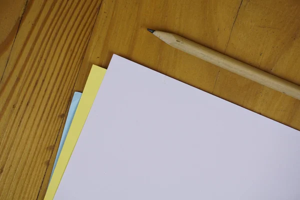 木桌上的铅笔和彩色的纸 — 图库照片