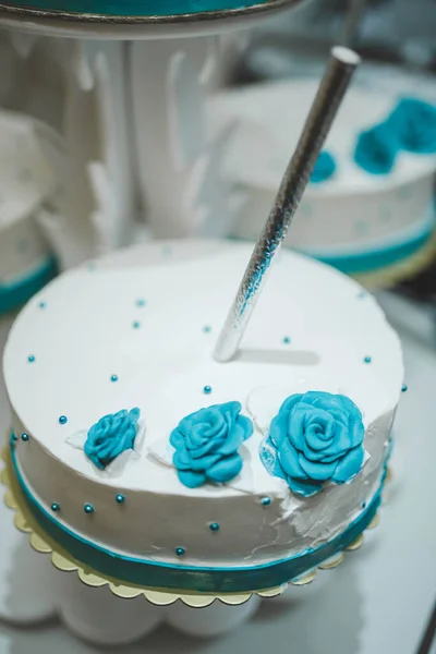 用蓝色玫瑰装饰在桌上盘子上的婚礼蛋糕的垂直照片 — 图库照片