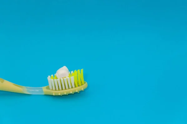 Closeup Toothpaste Squeezed Yellow Toothbrush Isolated Blue Background — Stock Photo, Image
