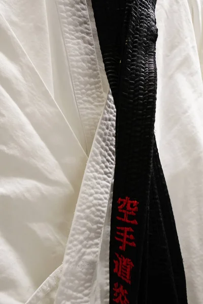 stock image BERGISCH GLADBACH, GERMANY - Nov 14, 2020: White karate suit, gi, on a hanger, with a black belt, obi, and the name of the owner in red Japanese letters