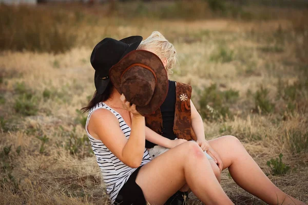 Женщина Сидящая Поле Сыном Закрывающим Лицо Ковбойской Шляпой — стоковое фото