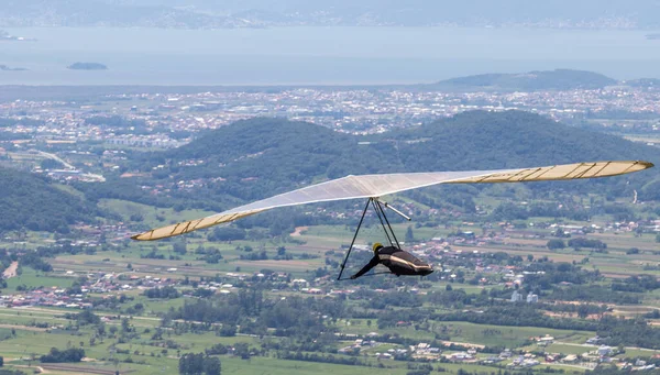 A person flying on the hang glider in the Brazilian mountain landscape