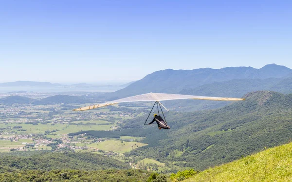 A person flying on the hang glider in the Brazilian mountain landscape