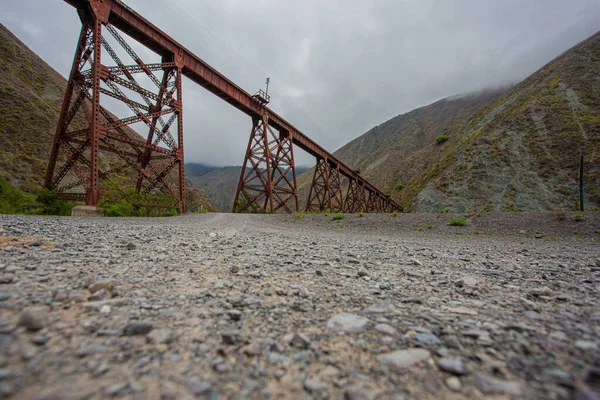 岩の丘に囲まれた錆びた金属製の橋の低角度ショット — ストック写真
