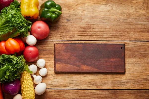 木の背景にまな板と新鮮な野菜のクローズアップショット — ストック写真