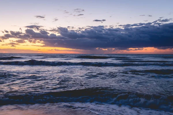 一道迷人的海浪般的海水拍下了一道迷人的落日的天空 — 图库照片