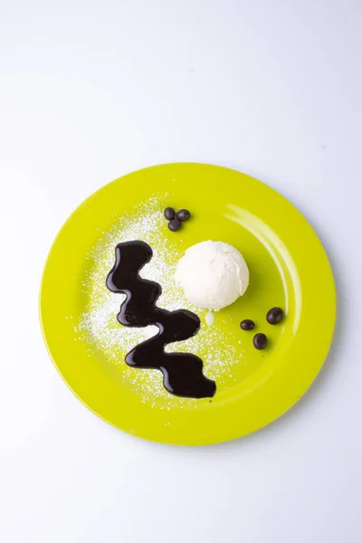 Вертикальный Снимок Ванильного Мороженого Расплавленным Шоколадом Зеленой Пластине Сером Фоне — стоковое фото