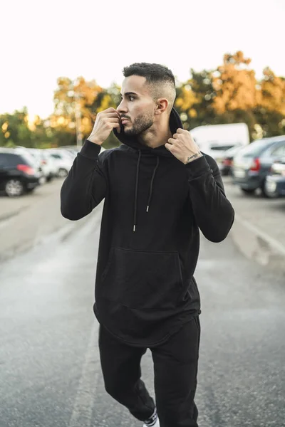 A street style of a European elegant man with a stylish haircut and beard in all back posing outdoors