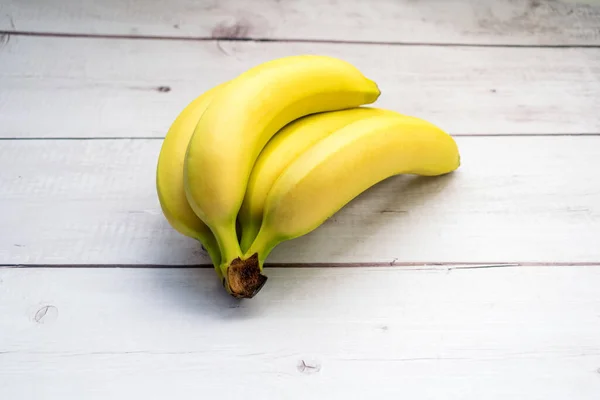 Zbliżenie Ujęcia Świeżych Dojrzałych Bananów Białej Drewnianej Powierzchni — Zdjęcie stockowe