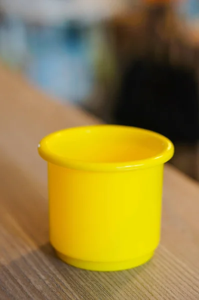 Pionowe Zdjęcie Selektywnej Ostrości Żółtego Plastikowego Kubka Zabawki Drewnianym Stole — Zdjęcie stockowe