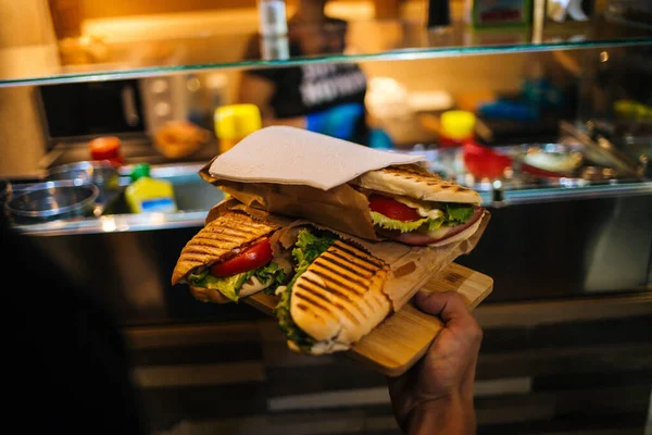 木製のトレイに3つの新鮮なサンドイッチを保持しているウェイターのクローズアップ — ストック写真
