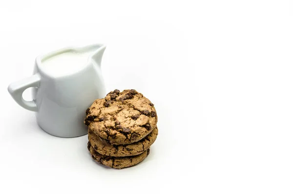 白い背景に単離された牛乳のピッチャーと自家製クッキーの垂直クローズアップショット — ストック写真