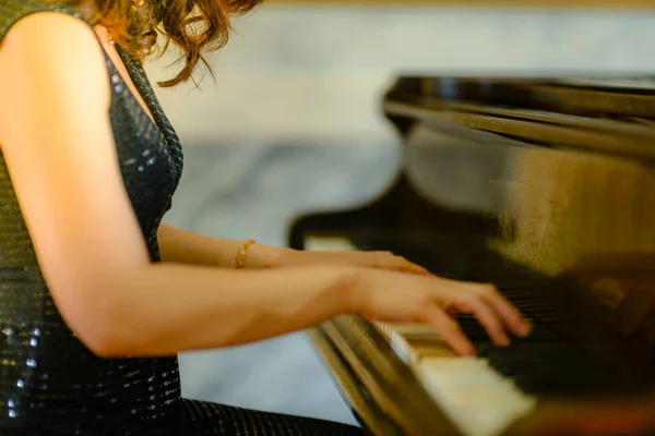 A closeup shot of a woman playing the piano