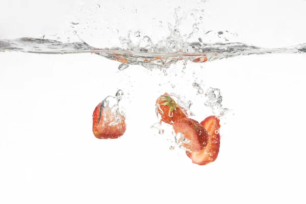 Die Aufgeschnittenen Erdbeeren Die Ins Wasser Spritzen — Stockfoto
