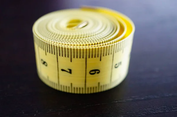 在木制表面上以厘米为单位的滚动黄色测量带的近照 — 图库照片