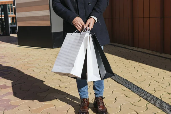 An unrecognizable man walking down the street with purchases