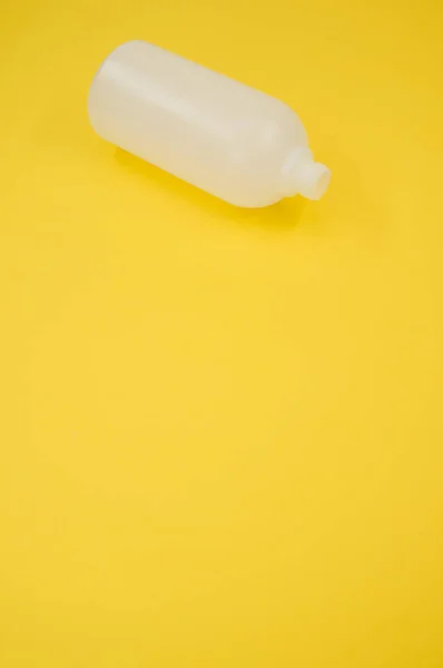 黄色底座上一个塑料瓶的垂直截图 — 图库照片