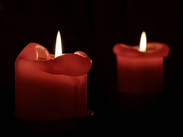 在黑暗的背景上点燃的两支红色蜡烛的特写 — 图库照片