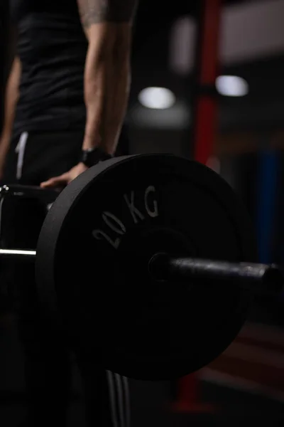 A vertical shot of a person lifting weights in a gym with a dark blurry background
