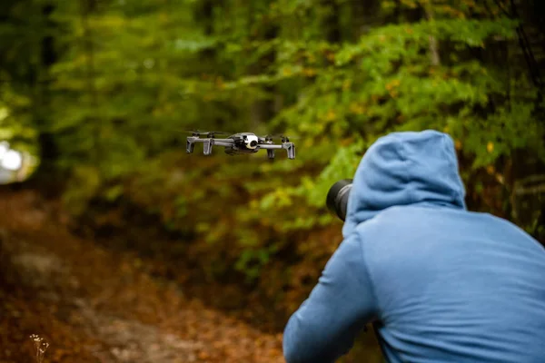 空中に浮かぶ無人機の写真を撮る青いパーカーを着た写真家 — ストック写真