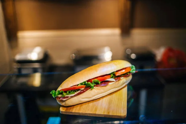 在木板上夹有意大利腊肠和蔬菜的美味新鲜三明治特写 — 图库照片